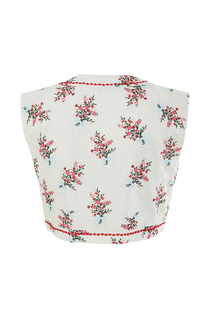 Madison Vest in white with pink and coral floral print, red pom-pom trim, and sleeveless silhouette
