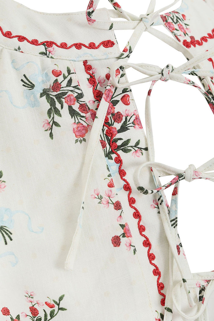 Madison Vest in ivory with embroidered floral print featuring red and pink blooms, green leaves, and red crochet trim along tie-front closure