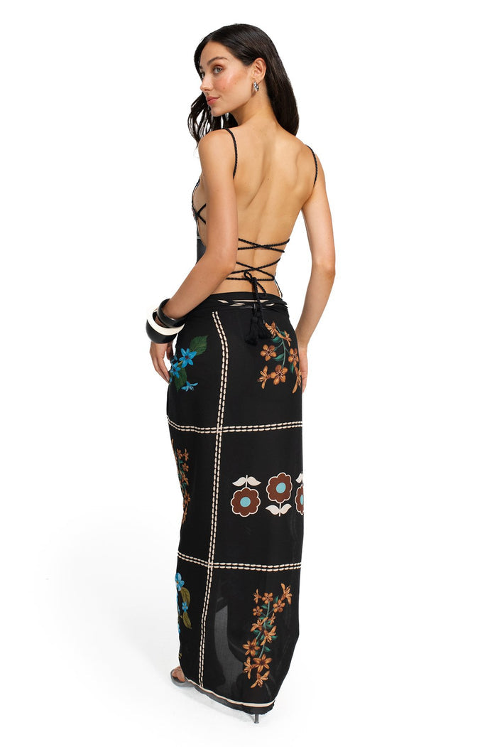Black pareo with embroidered pattern detail details in blue, orange, and green, accented with cream running stitch borders and handmade tassels at co…