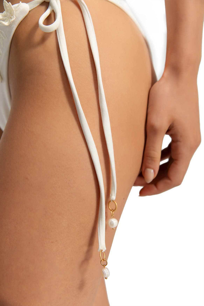 White bikini bottom with adjustable side ties featuring pearl charms and gold-tone rings