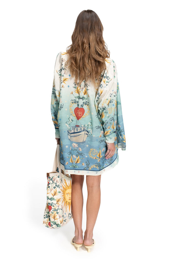 Nader Anastasia Shirt in cream to blue gradient with placement print of botanical florals, boat, and coral heart emblem, back view