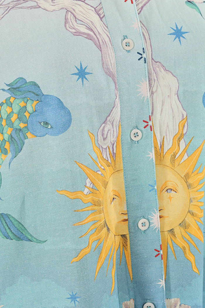 Light blue button-front shirt with celestial print featuring sun faces, stars, and decorative elements