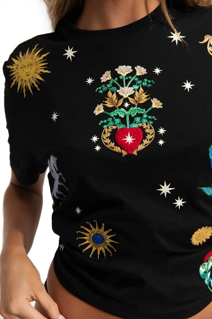 Black t-shirt with embroidered celestial details including suns, stars, flowers, and a red heart framed by golden leaves