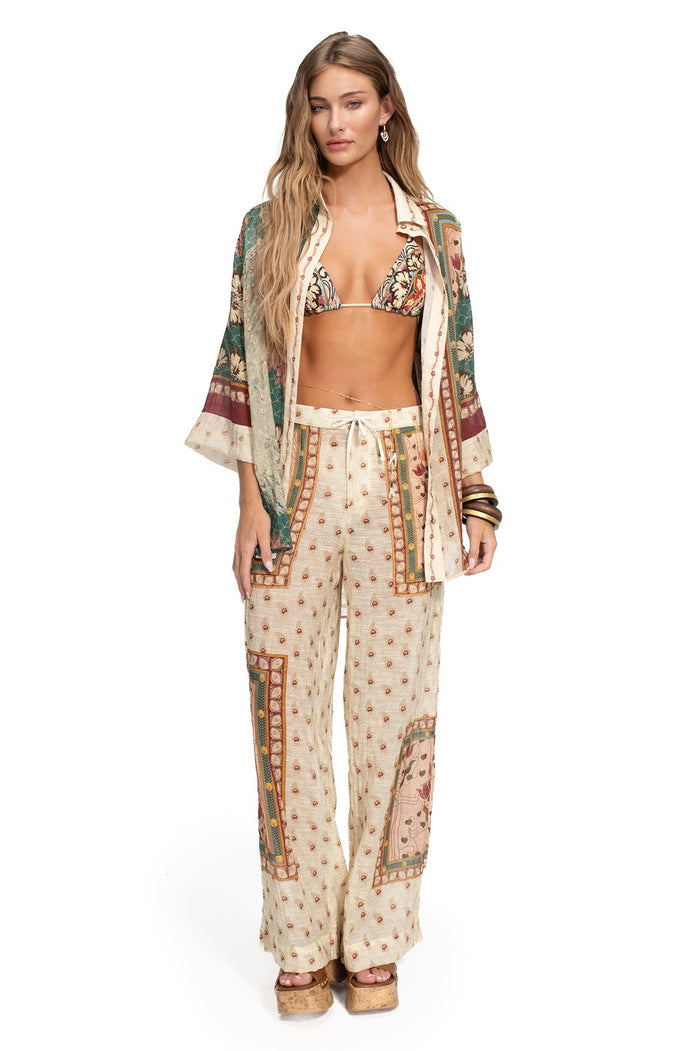 Wide-leg pants in cream with scattered terracotta dots and multicolor embroidered panel borders featuring geometric patterns and ornamental details