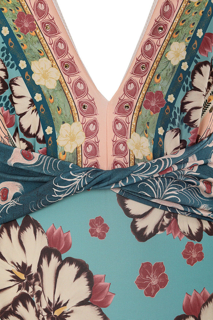 Nader Ellis one piece swimsuit with teal base, multicolor print featuring cream and pink florals, decorative banded stripes, and teal twisted knot de…