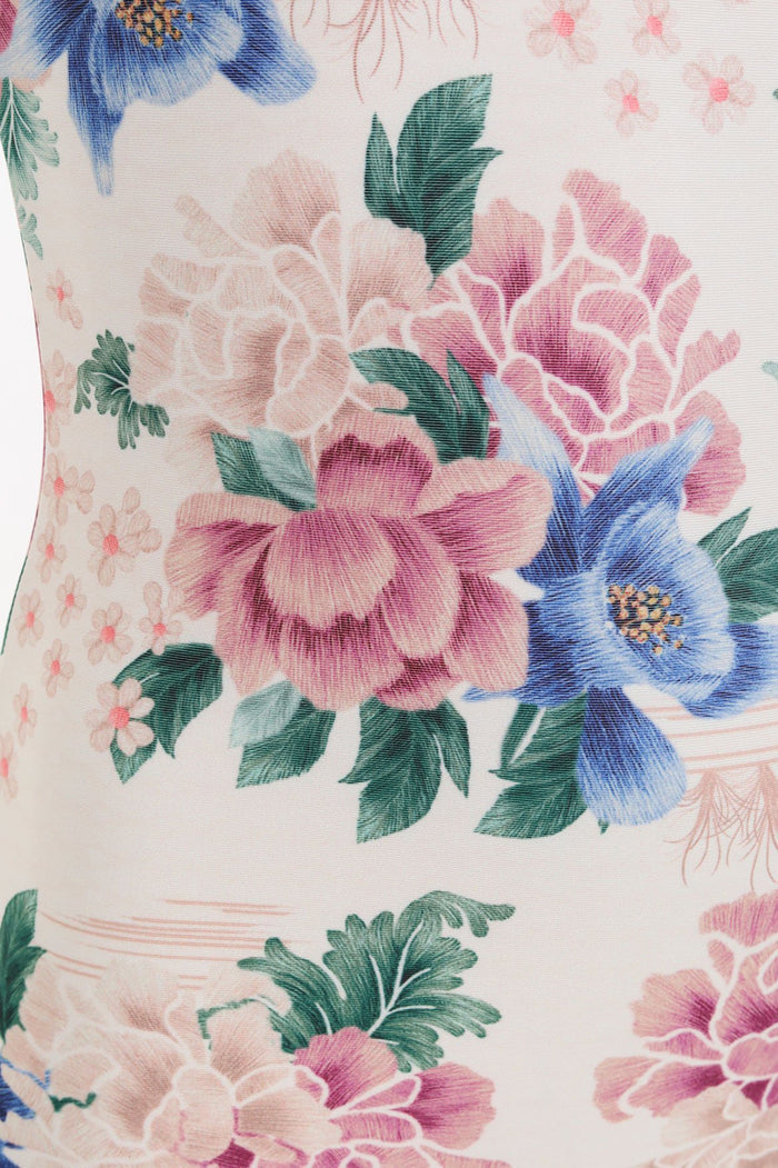 Cream one-piece swimsuit with pink, blue and beige pattern detail print and green leaves