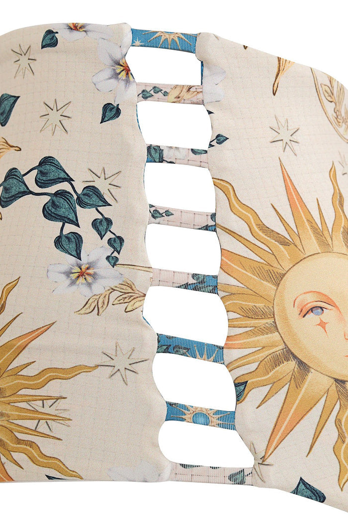 High-waist bikini bottom in cream with botanical print featuring teal leaves, white flowers, yellow palm fronds and stars, ladder cut-out detail at c…