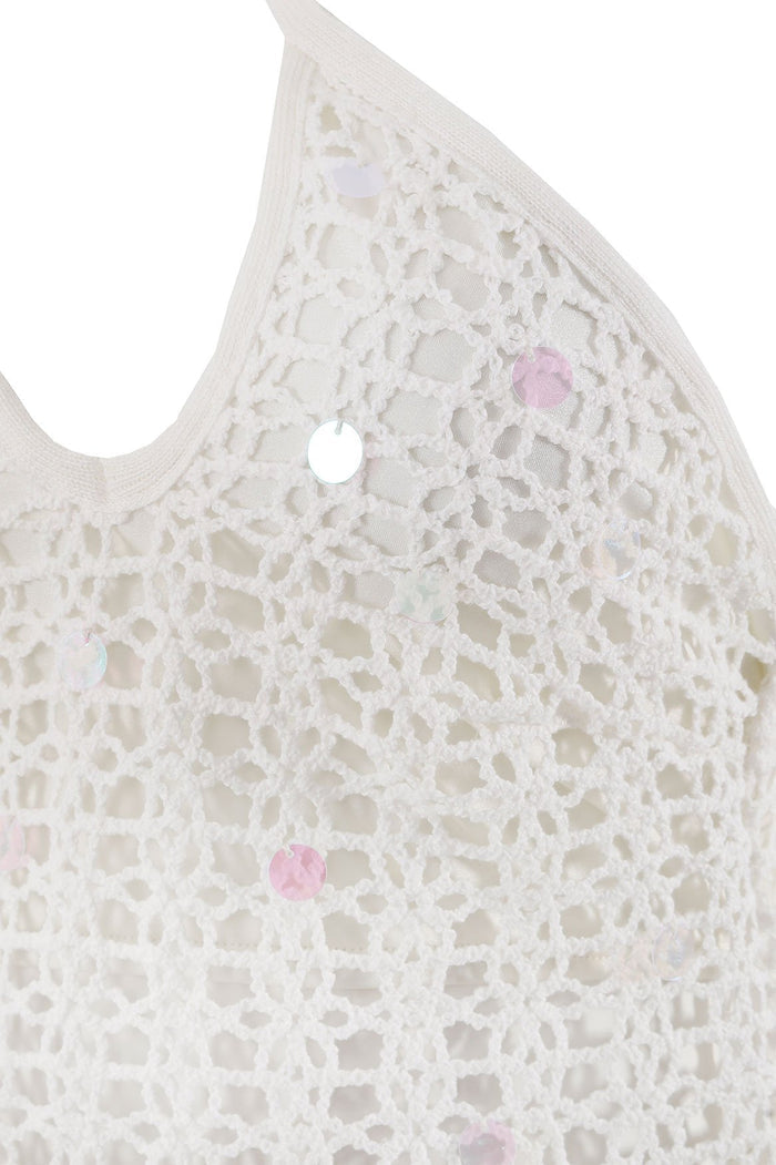 White halter dress with intricate openwork crochet texture and pink iridescent sequin details