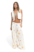 Ivory vest with multicolor embroidered trim and pattern detail details, paired with matching wide-leg pants featuring sun, star, and pattern detail e…