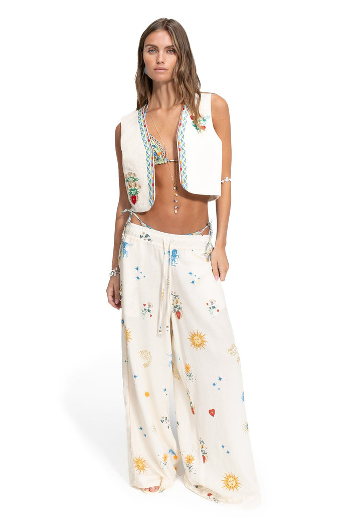 Ivory vest with multicolor embroidered trim and pattern detail details, paired with matching wide-leg pants featuring sun, star, and pattern detail e…