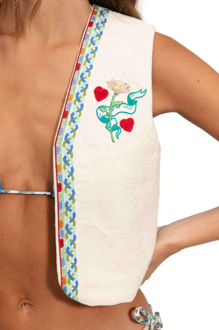 White vest with multicolor embroidered scalloped trim and turquoise pattern detail embroidery with red heart details