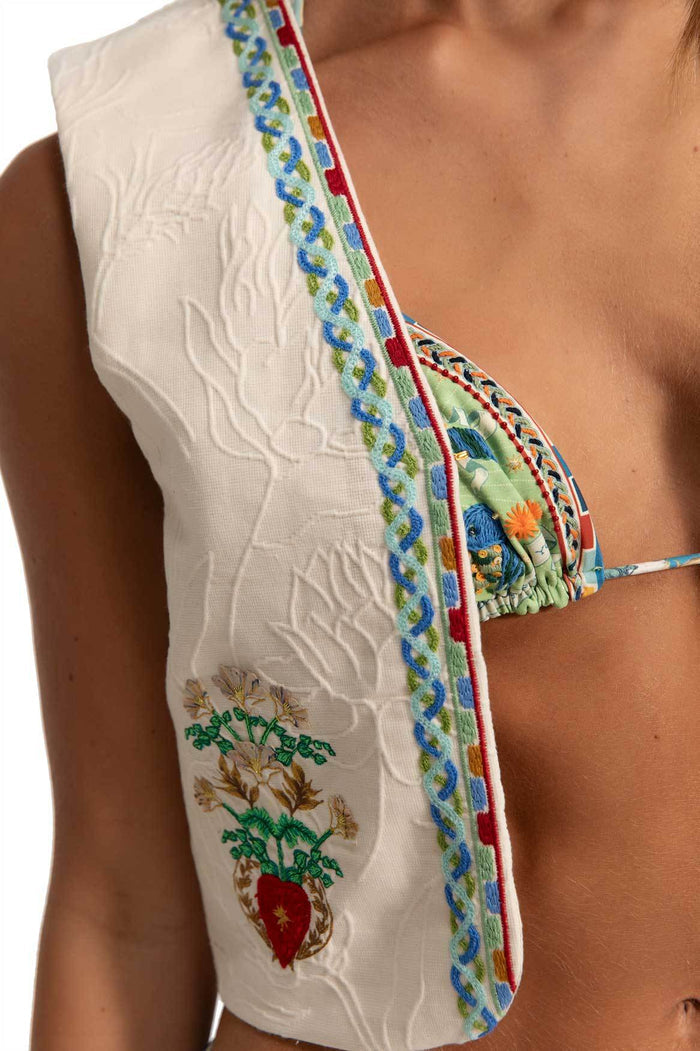 White embroidered vest with multicolor pattern detail trim, textured botanical pattern, and inner printed lining detail