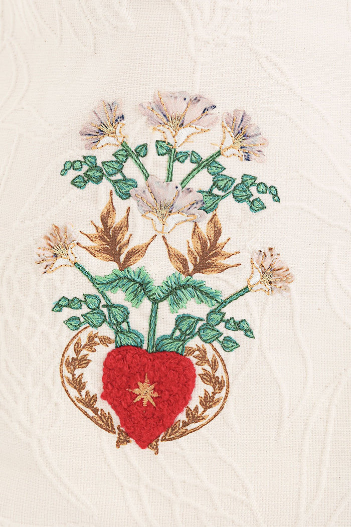 Nader Mabel Vest in cream with embroidered red heart surrounded by green foliage, gold leaves, and white flowers