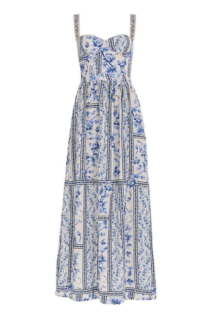 Nader Marcia maxi dress in white with blue pattern detail print arranged in vertical panels, featuring structured bodice with embellished straps and…