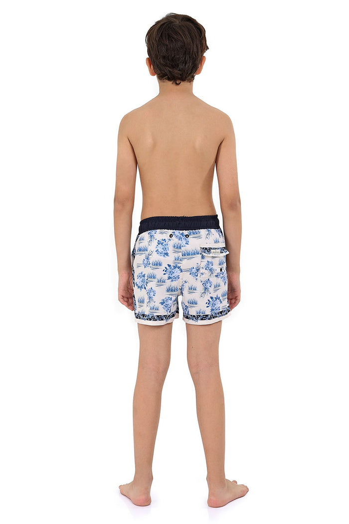 Boys' swim trunks in white with blue toile-inspired scenic print and navy contrast waistband and trim, back view