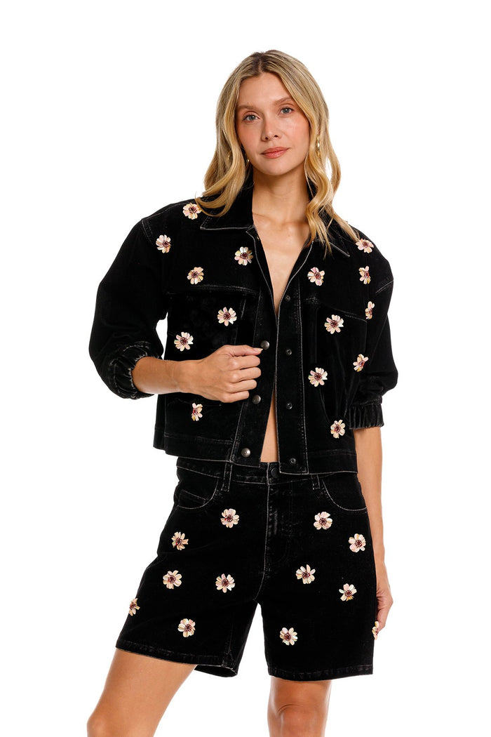 Black denim shorts with pink and beige handmade floral embroidery scattered across the front
