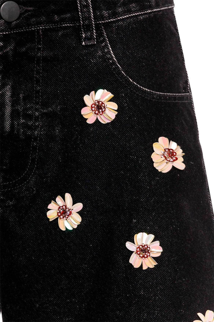Black denim shorts with handmade floral embroidery in pink, cream, and yellow tones scattered across the front