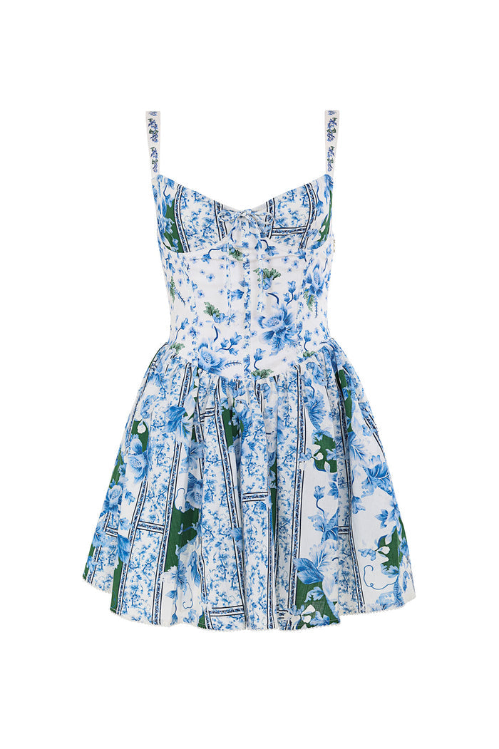 White dress with blue pattern detail print, structured bodice with underwire detail, and pleated skirt with green leaf accents and black trim