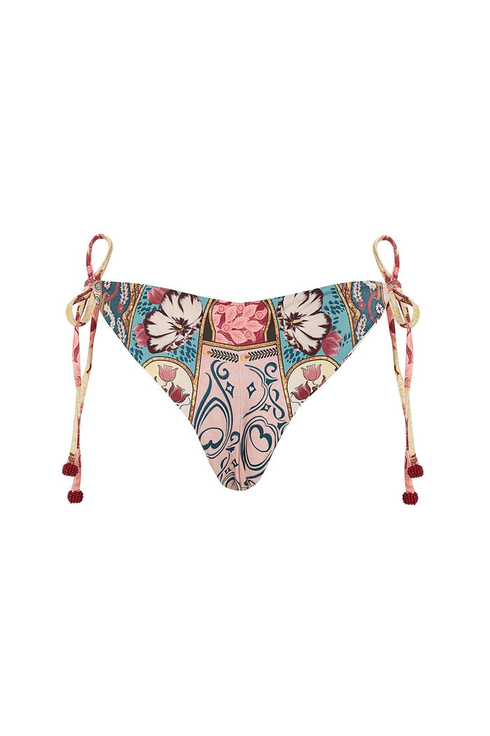 Nader Tammy bikini bottom with side ties and handmade pompom tie-ends, featuring multicolor ornamental print with florals, scrollwork, and tile-inspi…