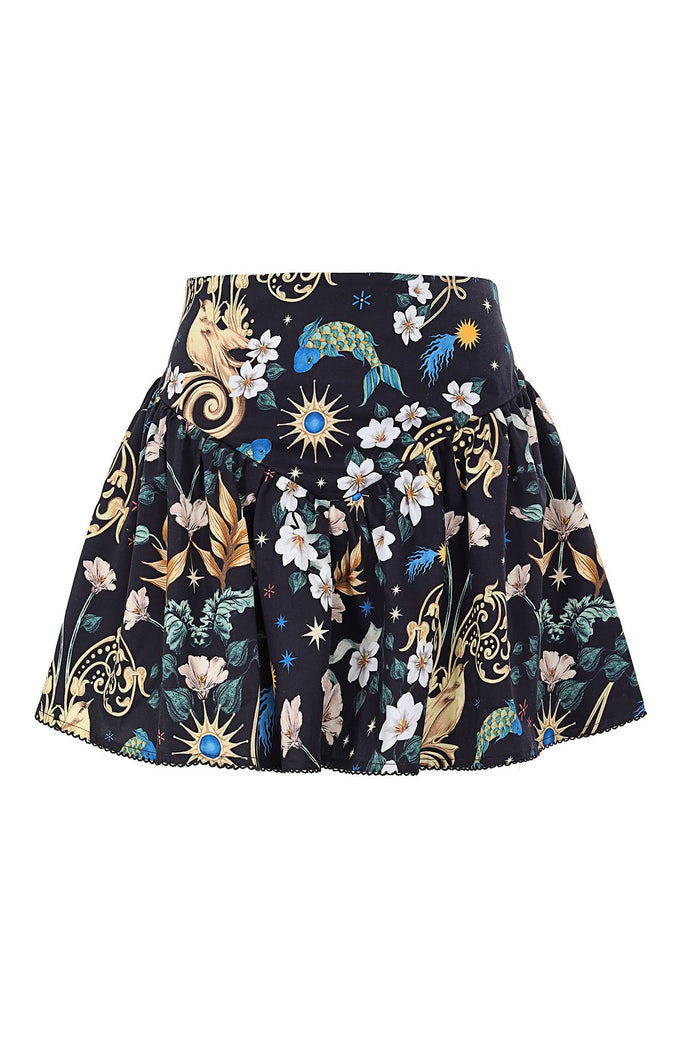 Black mini skirt with flared silhouette featuring white flowers, golden sun bursts, blue peacock, and botanical print with decorative trim hem