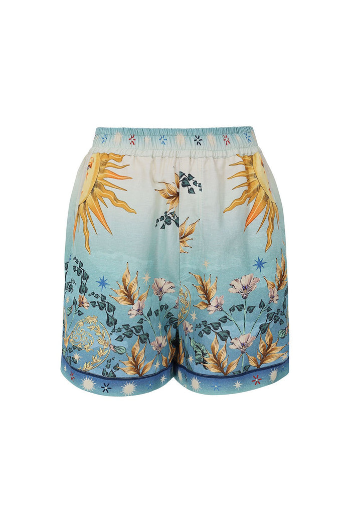 Nader Watts Shorts in gradient blue with golden sunburst print, botanical stems, and star details along elastic waistband and hem