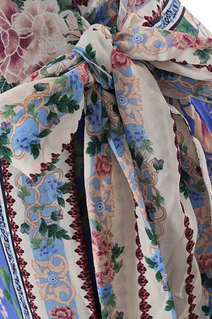 Nader Ziara wrap skirt in cream with vertical floral stripes in blue, pink and green, bordered by burgundy scalloped trim, tied at waist