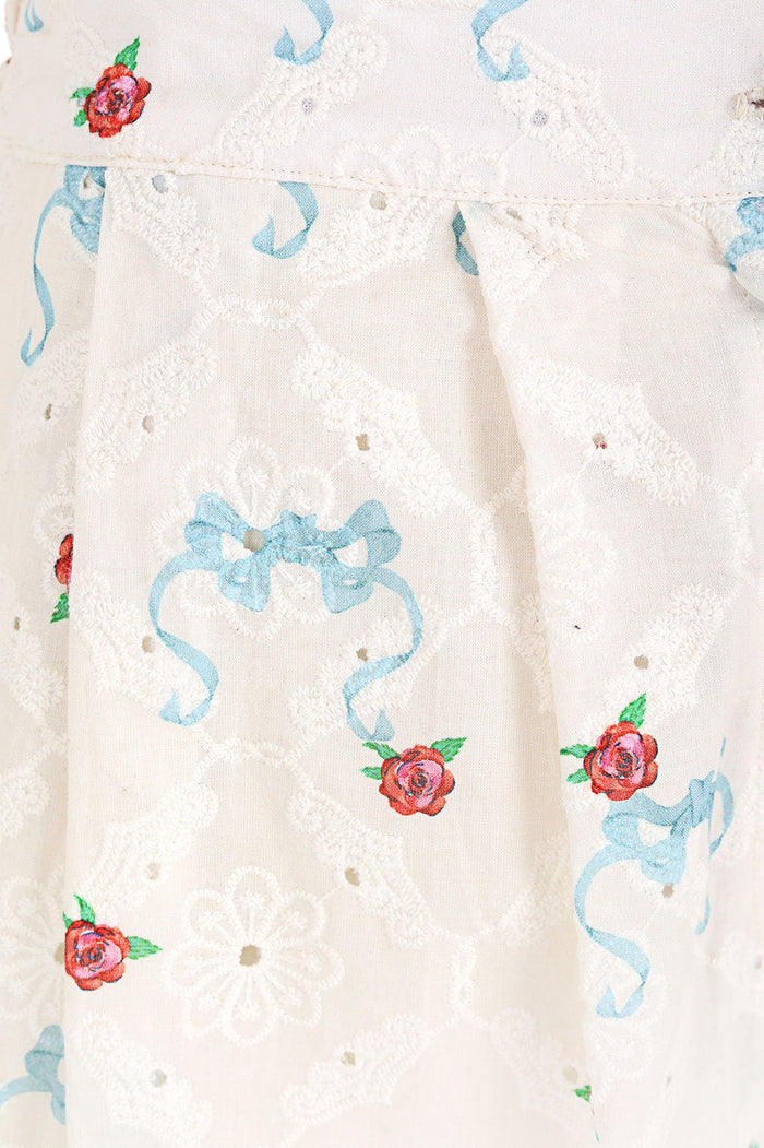 White eyelet shorts with embroidered blue ribbon bows and coral flowers throughout