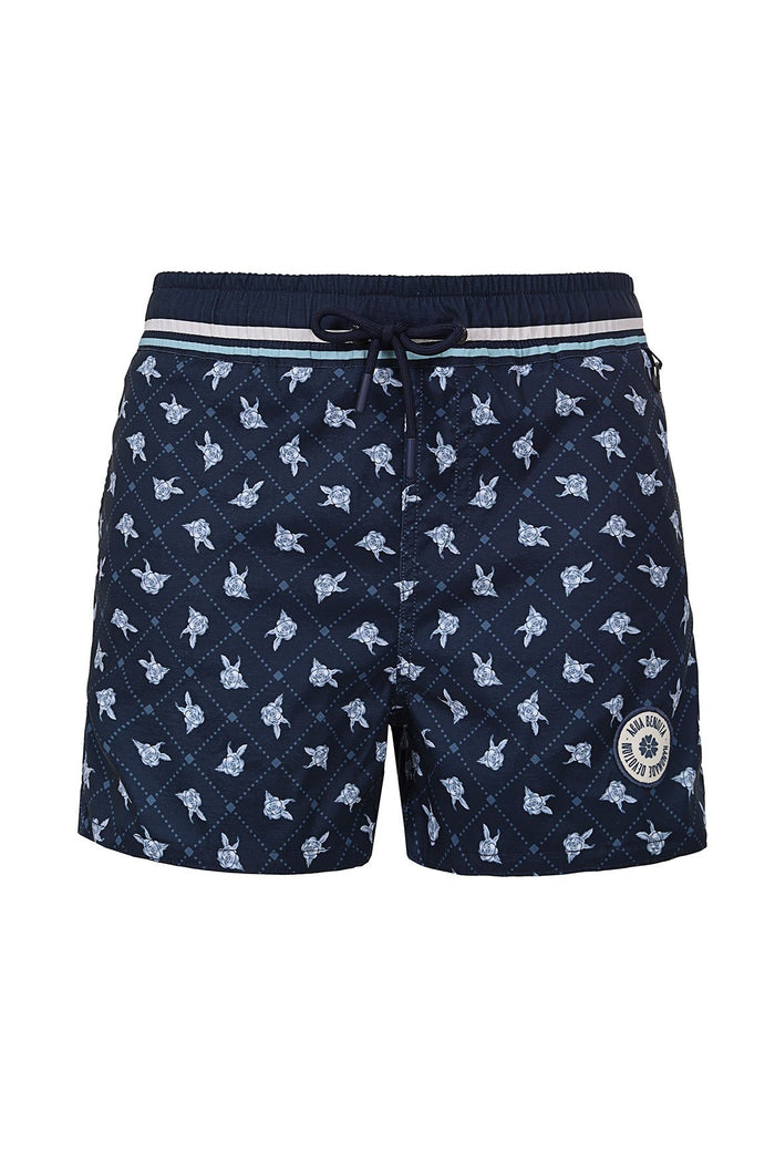 Navy swim trunks with light blue turtle silhouettes over diagonal lattice pattern, striped elastic waistband, and circular emblem patch