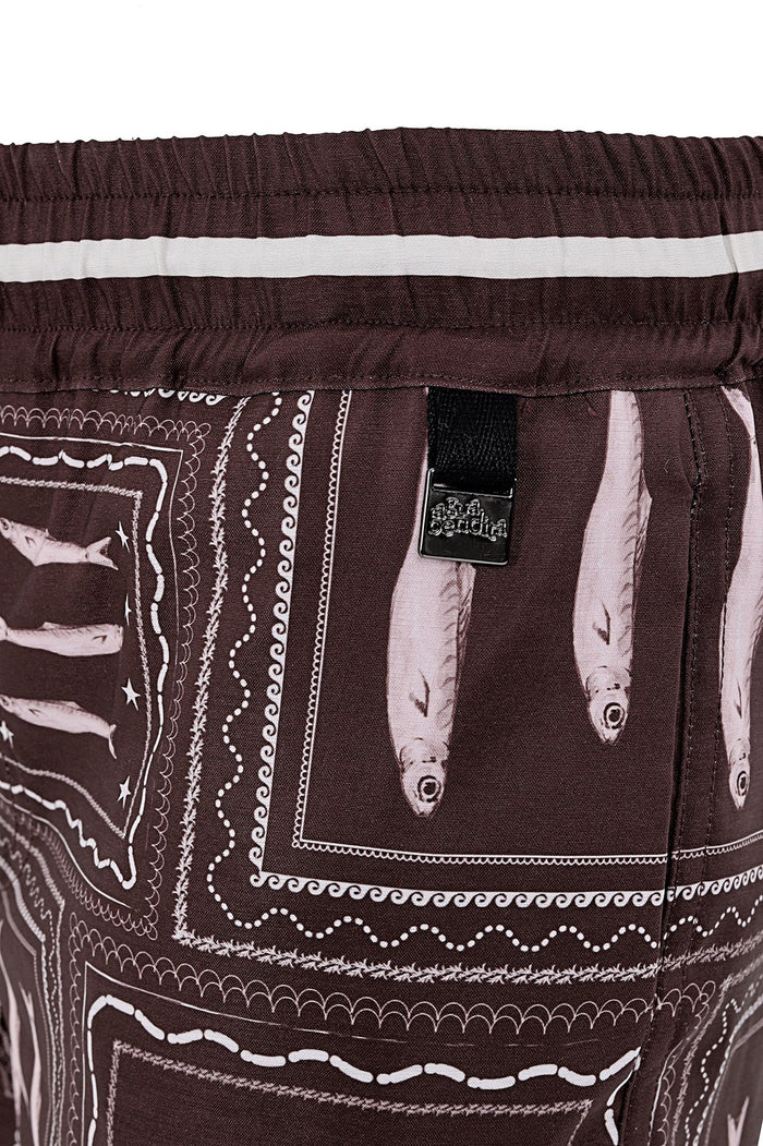 Brown swim trunks with white geometric print and decorative embroidery details, featuring an elastic waistband with white stripe