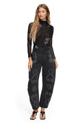 Black sheer bodysuit with white embroidered details and black rhinestone-embellished high-waist jeans