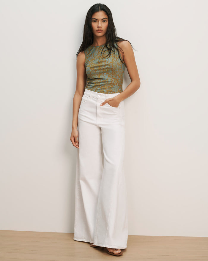 Veronica Beard Sleeveless green and brown patterned knit top with white wide-leg jeans.