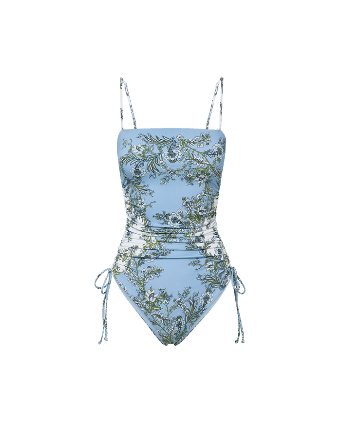 Veronica Beard Light blue one-piece swimsuit with white and green floral print, ruched sides, and adjustable ties.