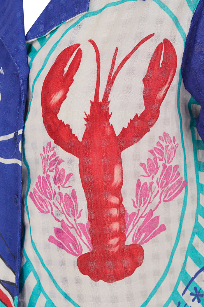 Short-sleeve button-up shirt with vibrant red lobster and pink coral print on white background, turquoise trim and blue geometric panels