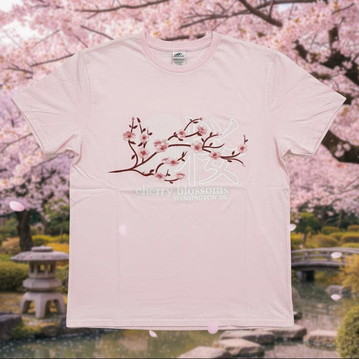 Pink t-shirt with floral design held by a person against a neutral background