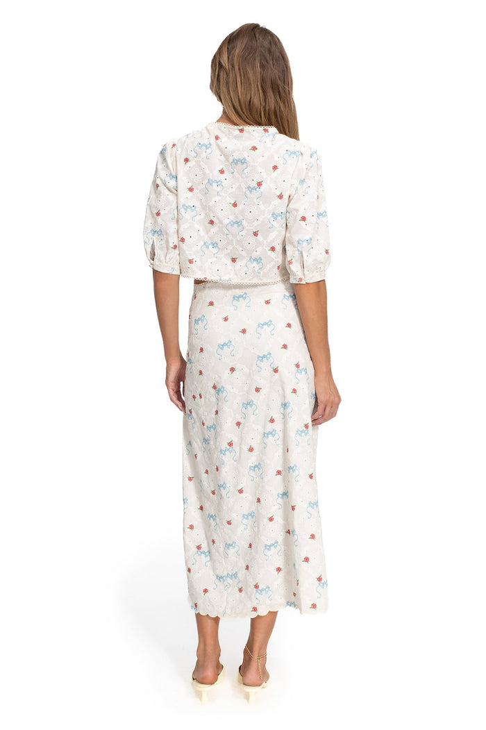 White crop top with blue and coral pattern detail print on eyelet fabric, puff sleeves, and scalloped trim detail, back view
