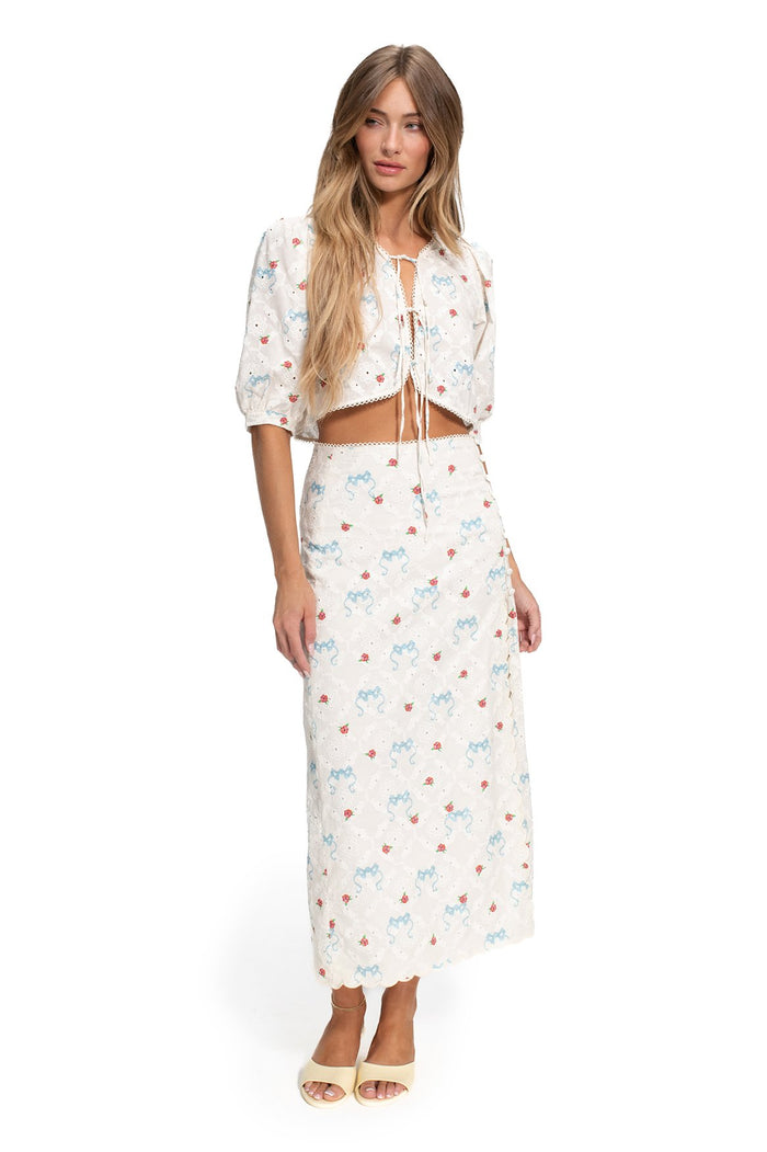 White eyelet maxi skirt with scattered blue and coral pattern detail print, puff-sleeve cropped tie-front top with scalloped trim