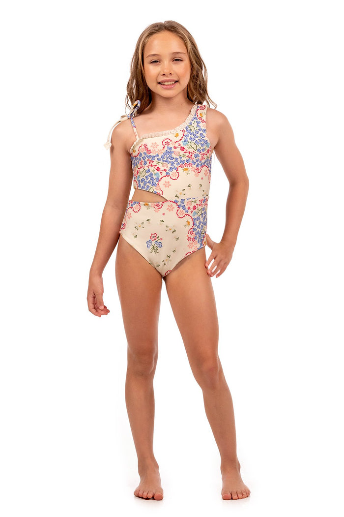 Girls' one-piece swimsuit in cream with blue and pink pattern detail print, asymmetric neckline, cutout waist, and ruffled shoulder straps