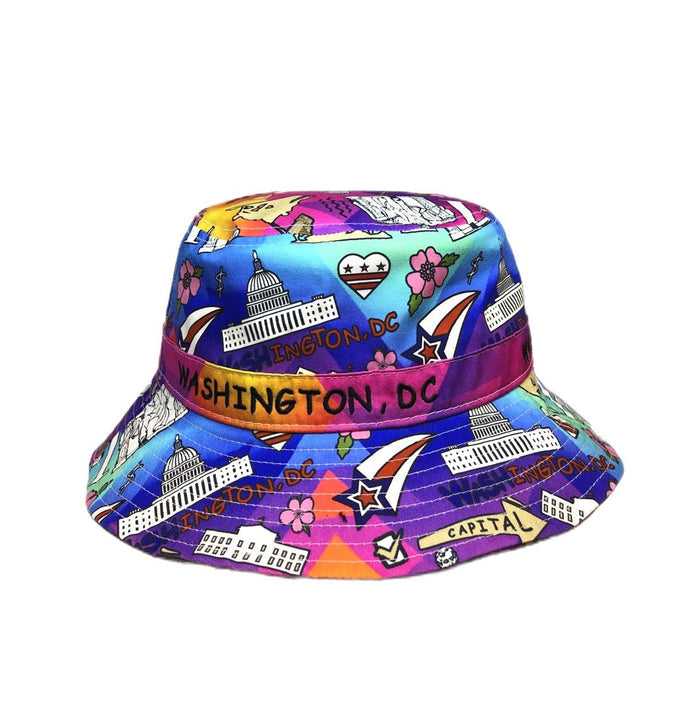 A colorful bucket hat featuring a vibrant Washington, DC themed print with illustrations of landmarks, stars, and the phrase 'CAPITOL' on a purple band, set against a plain white background.