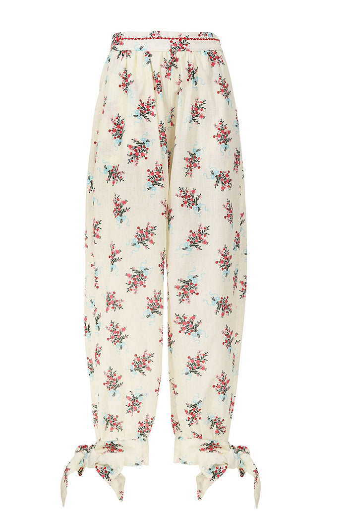Silvia Pants in cream with scattered floral print in red, pink, and blue tones, featuring elastic waist with embroidered trim and adjustable ankle ti…