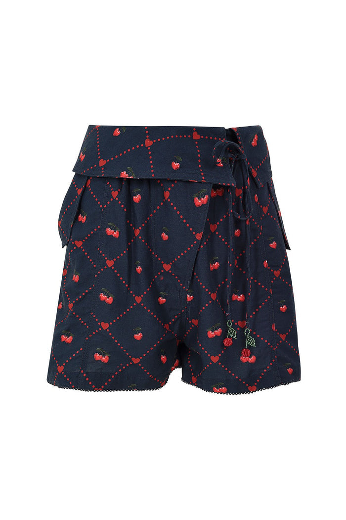 Navy shorts with red cherry print in diamond lattice pattern, featuring wrap-style waist, scalloped hem, and beaded cherry tie detail