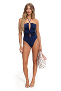 Navy blue one piece swimsuit with cross-front halter neckline, ruched center cutout details, and handmade tie accents