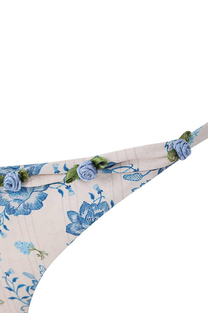 Tammy bikini bottom in cream with blue pattern detail print and handmade strap details featuring fabric rosettes