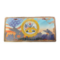 A United States Army license plate featuring the official seal and silhouettes of soldiers, photographed inside its clear plastic protective sleeve on a reddish-brown desk surface.
