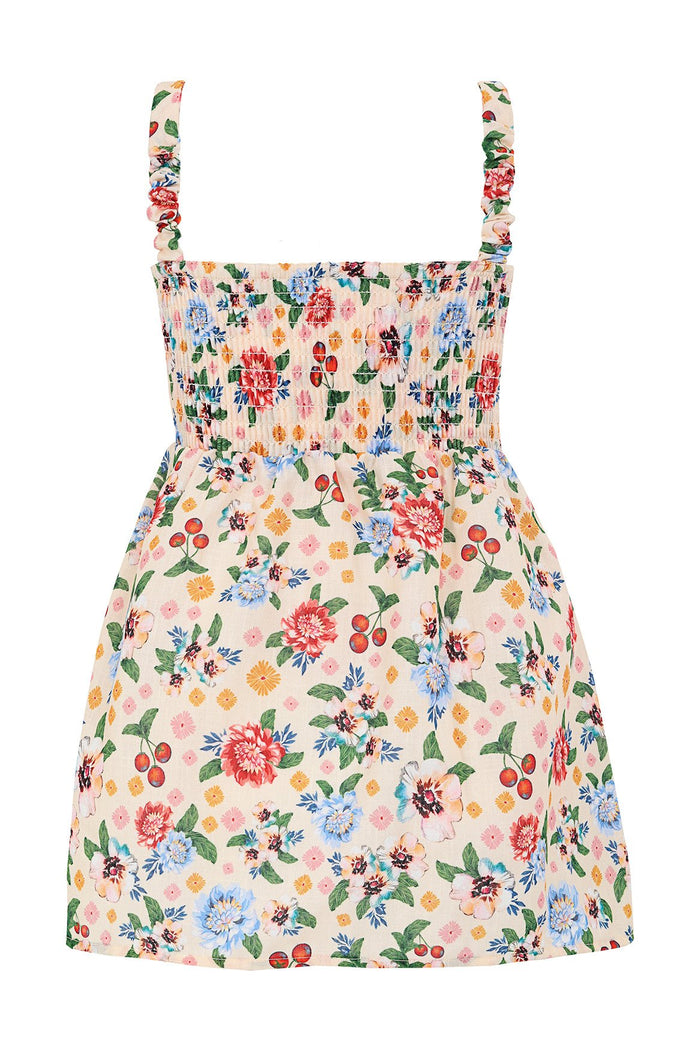 Cream kids' dress with smocked bodice, ruffle straps, and colorful pattern detail print with green leaves and scattered cherries