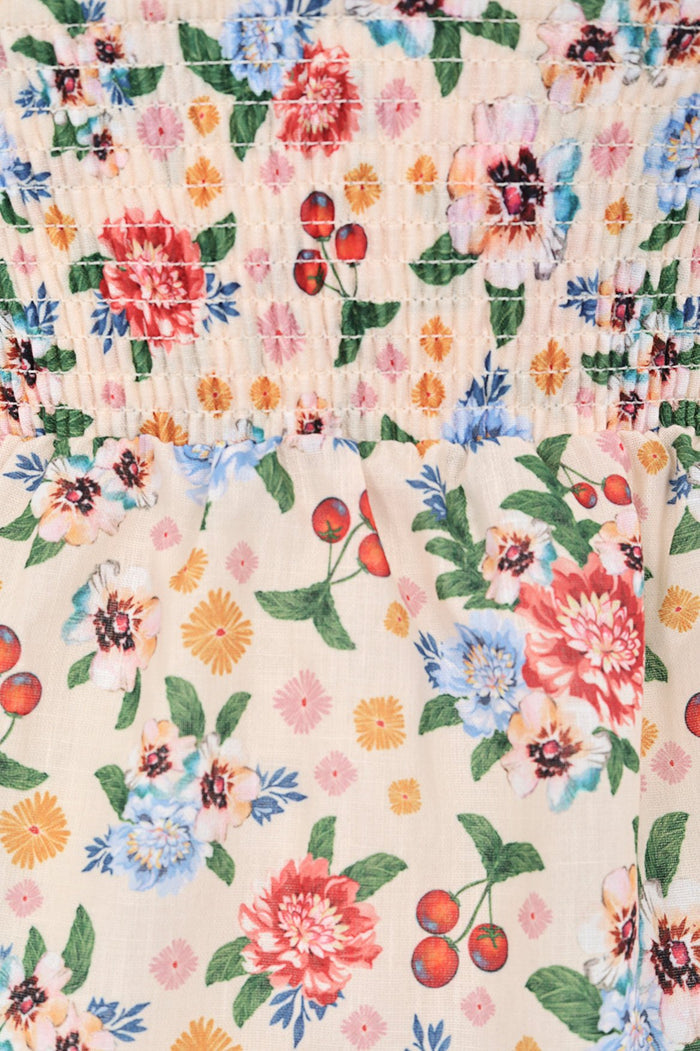 Cream smocked dress with multicolor pattern detail print featuring dahlias, daisies, cherries and green leaves