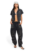Black cropped denim shirt with rhinestone and silver stud embellishments forming geometric patterns along the front panels and shoulders