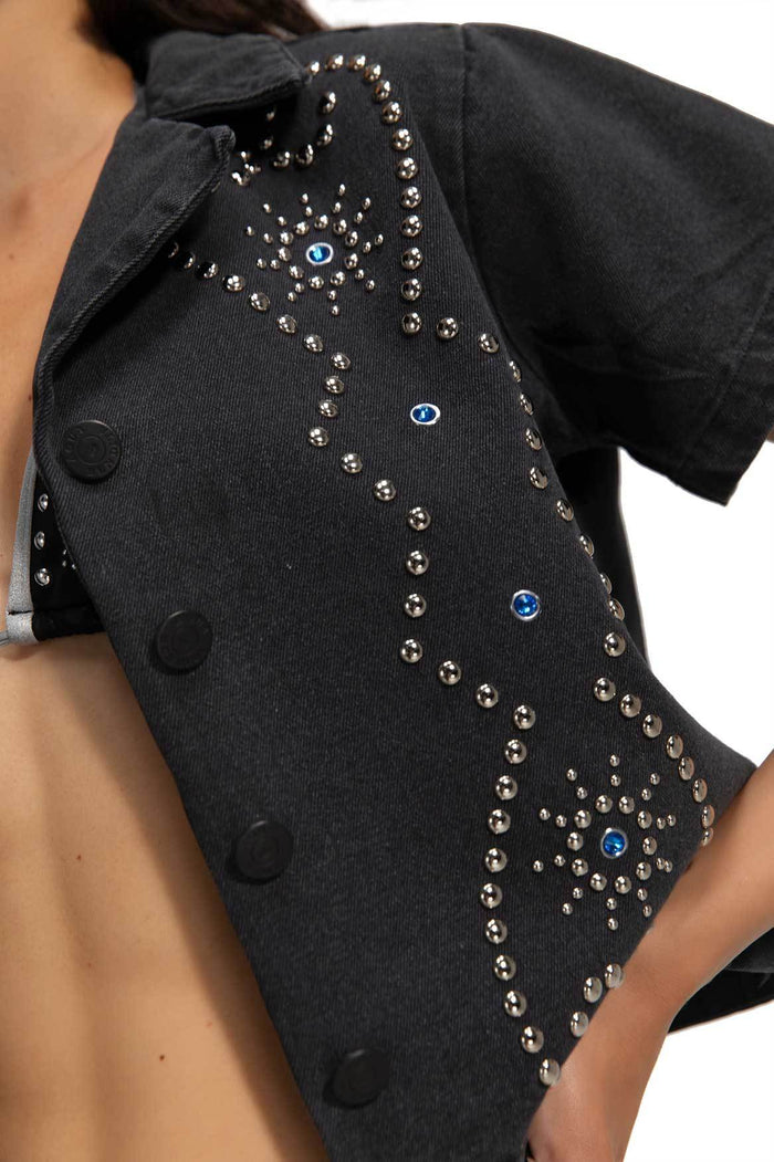 Black cropped denim shirt with silver studded and blue rhinestone embellishments in geometric sunburst pattern, button-front closure and structured c…
